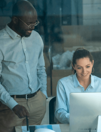 Um homem e uma mulher olhando para a tela de um notebook e sorrindo.